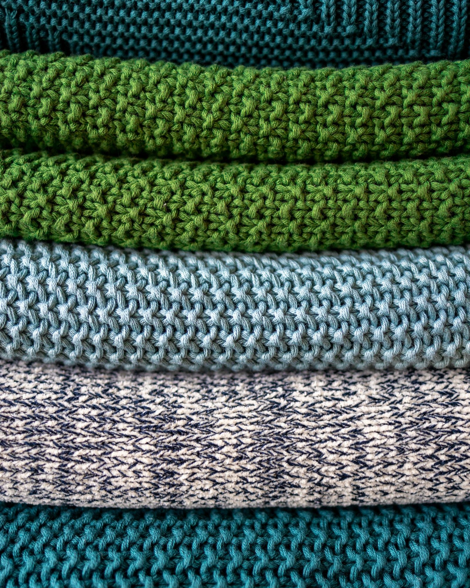 stack of knitwear in green and blue tones