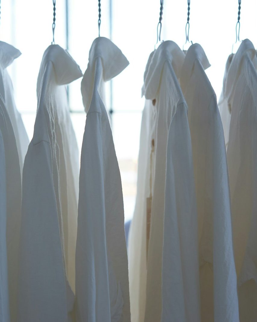 white shirts hanging on a rail by a window